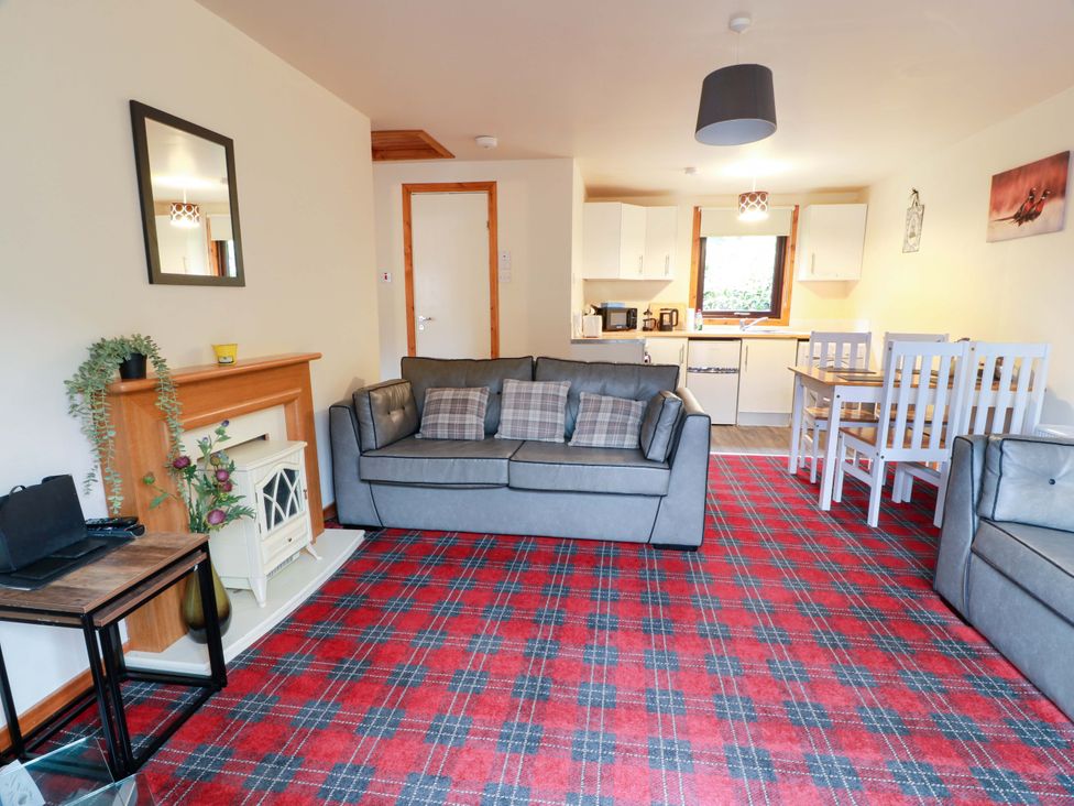 A living room with a sofa and dining table at Thistle Lodge in Dunoon