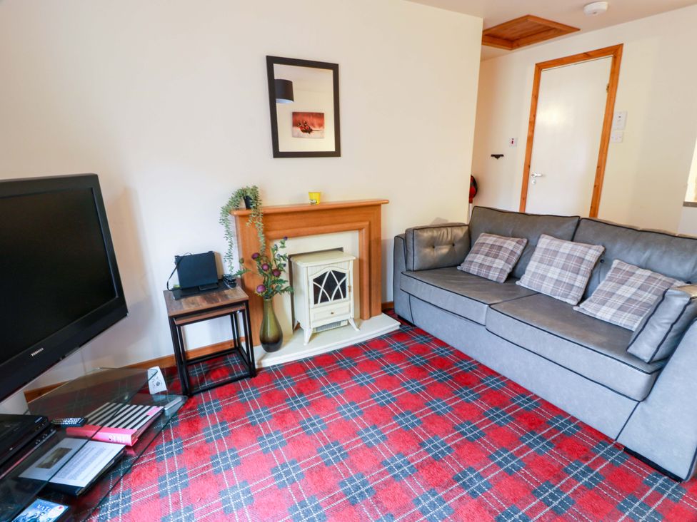 A living room with a sofa and television at Thistle Lodge in Dunoon