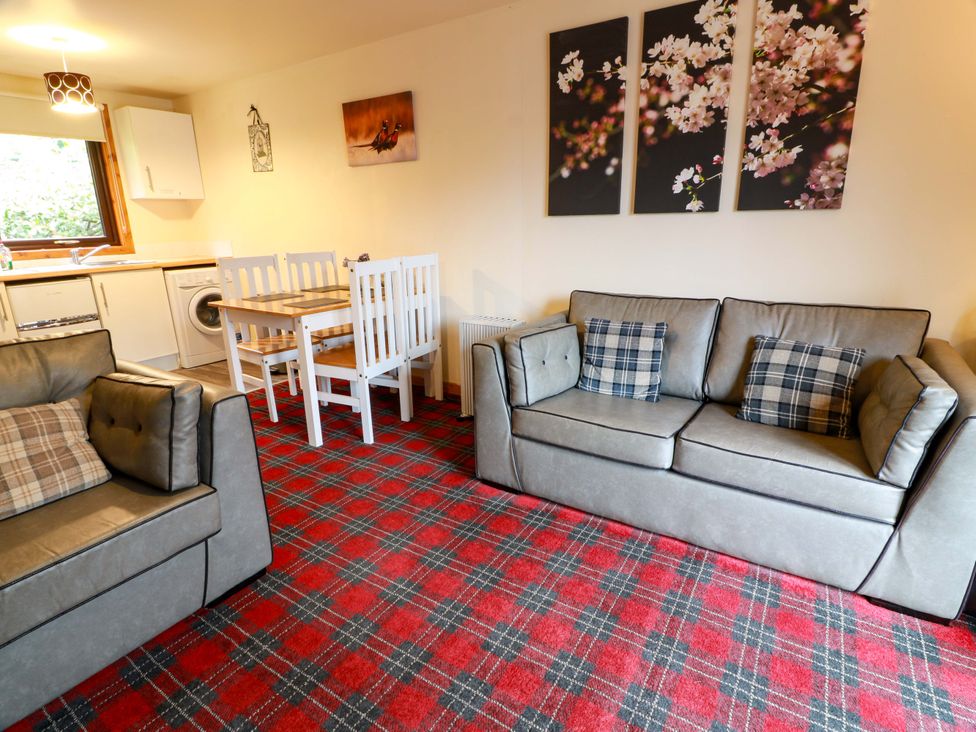 A living room with a couch and dining area at Thistle Lodge in Dunoon