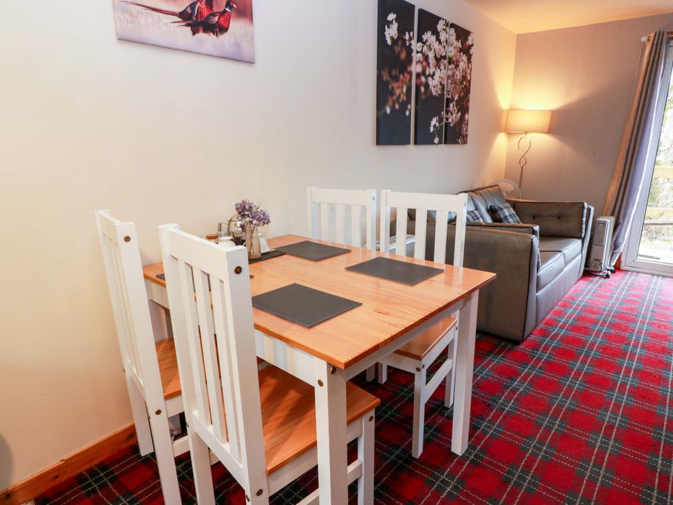 A dining table with chairs and a sofa at Thistle Lodge in Dunoon