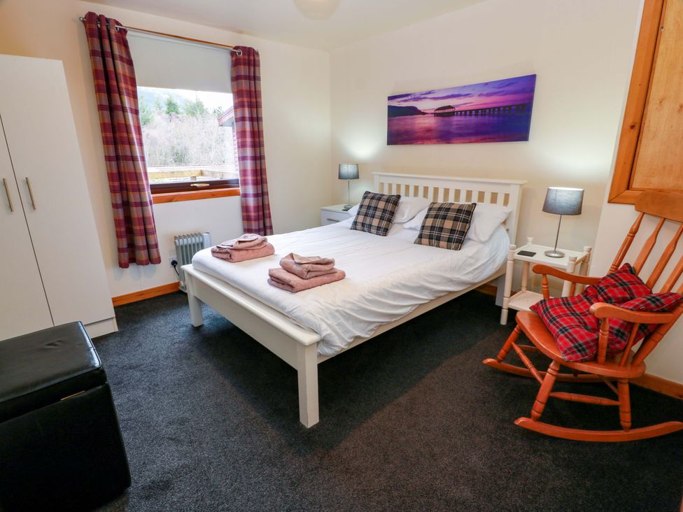 A bedroom with a bed and a rocking chair at Thistle Lodge in Dunoon