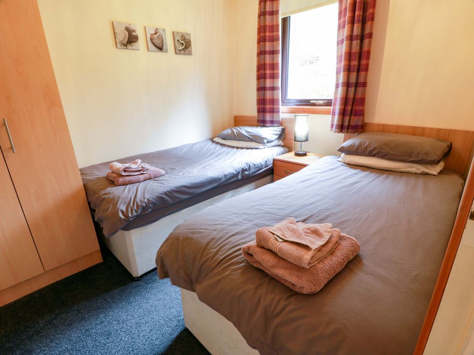 A bedroom with two beds and a bedside table at Thistle Lodge in Dunoon