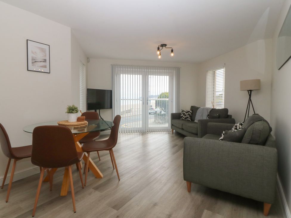 A living room with a dining area and a television at 2 Ocean View Colwyn Bay