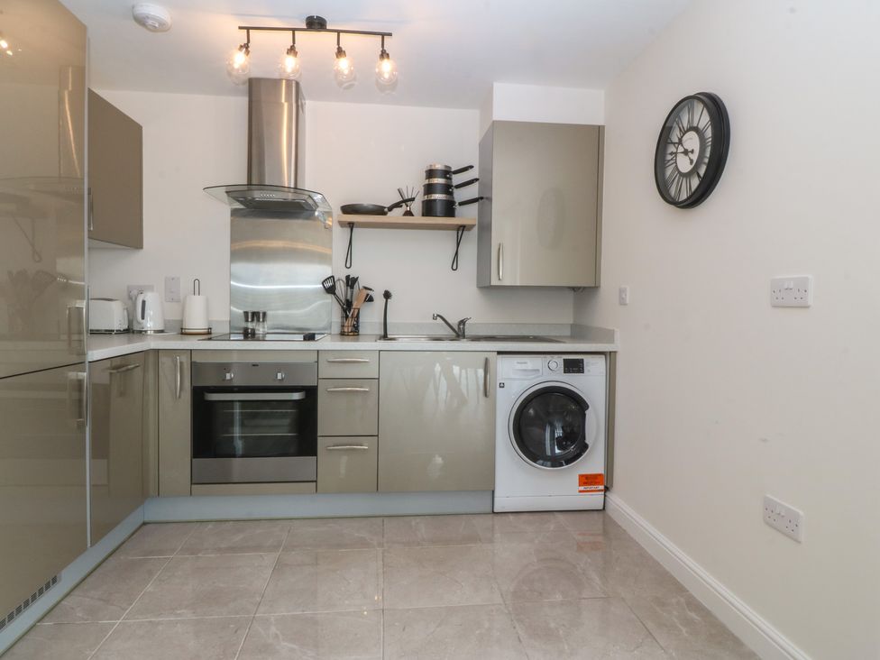 A kitchen featuring a sink, washing machine, oven, and utensils at 2 Ocean View in Colwyn Bay