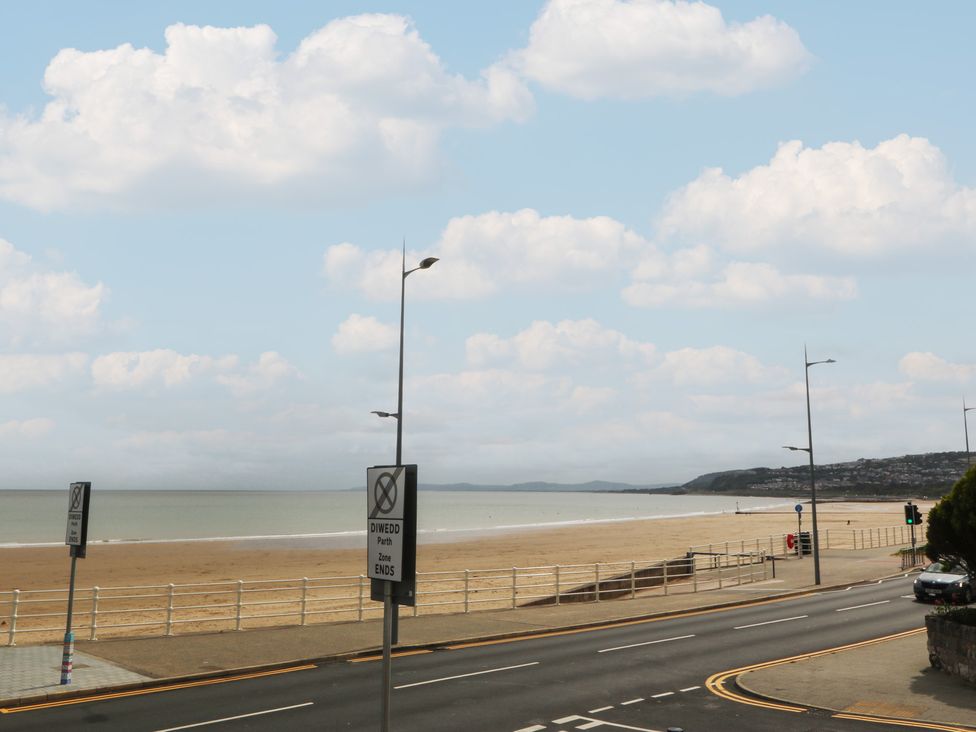 A beach and ocean view with signs and road at 2 Ocean View Colwyn Bay