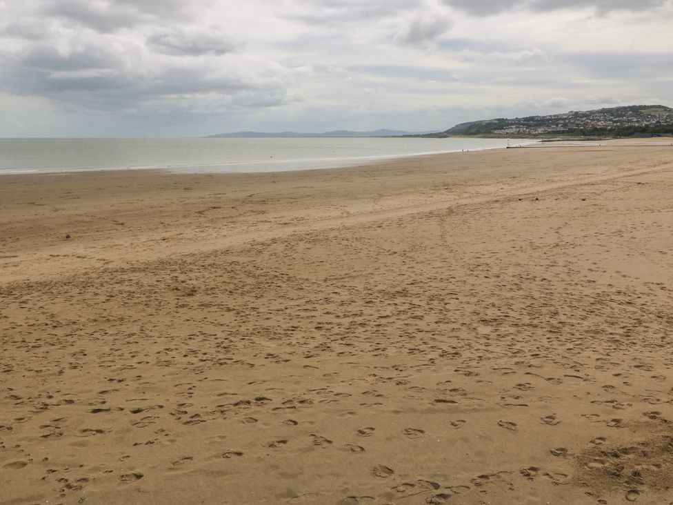 A beach with footprints and water at 2 Ocean View in Colwyn Bay