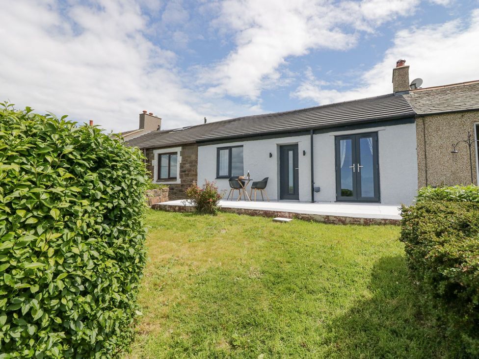 A house with a patio and table in the garden at Victroneen Cottage in Whitehaven