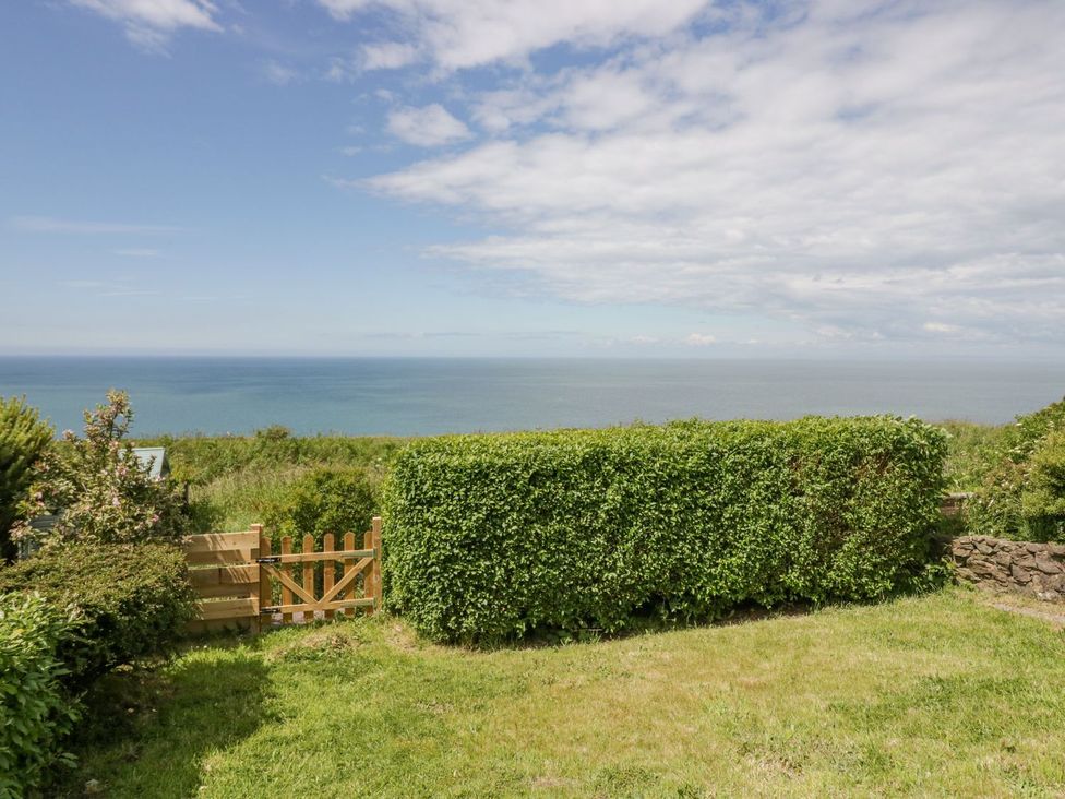 A garden with a hedge and gate overlooking the ocean at Victroneen Cottage in Whitehaven