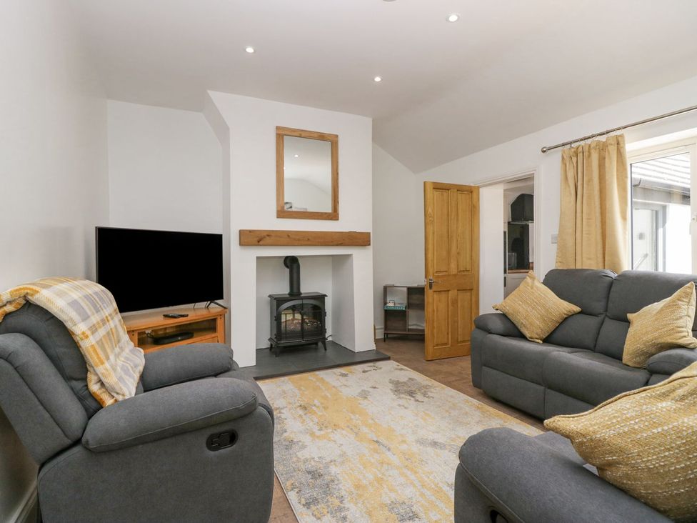 A living room with a fireplace and television at Victroneen Cottage in Whitehaven