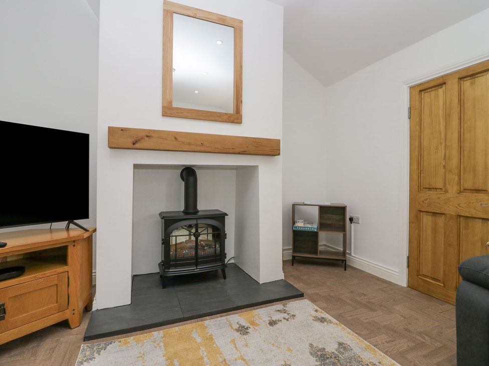 A living room with a fireplace and television at Victroneen Cottage Whitehaven