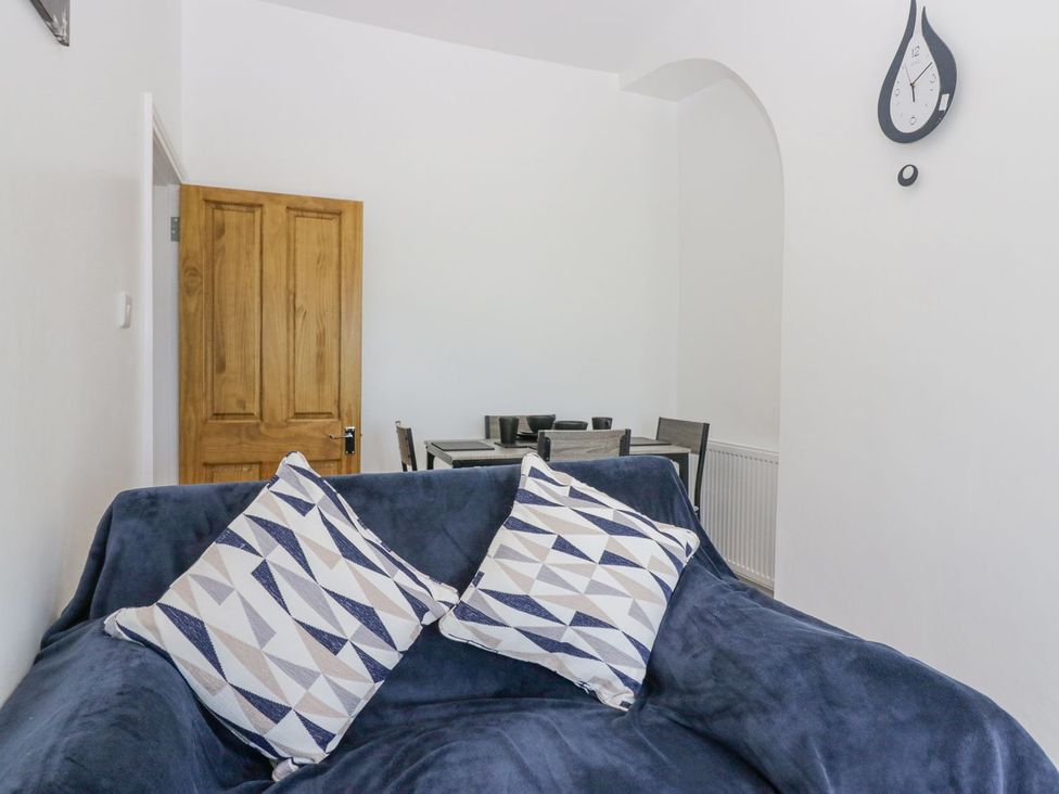 A living room with a sofa and dining area at Victroneen Cottage Whitehaven