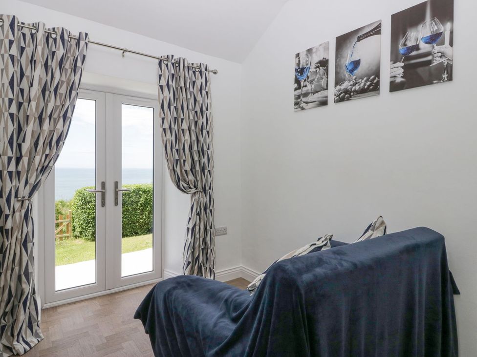 A living room with a sofa and double doors leading outside at Victroneen Cottage in Whitehaven