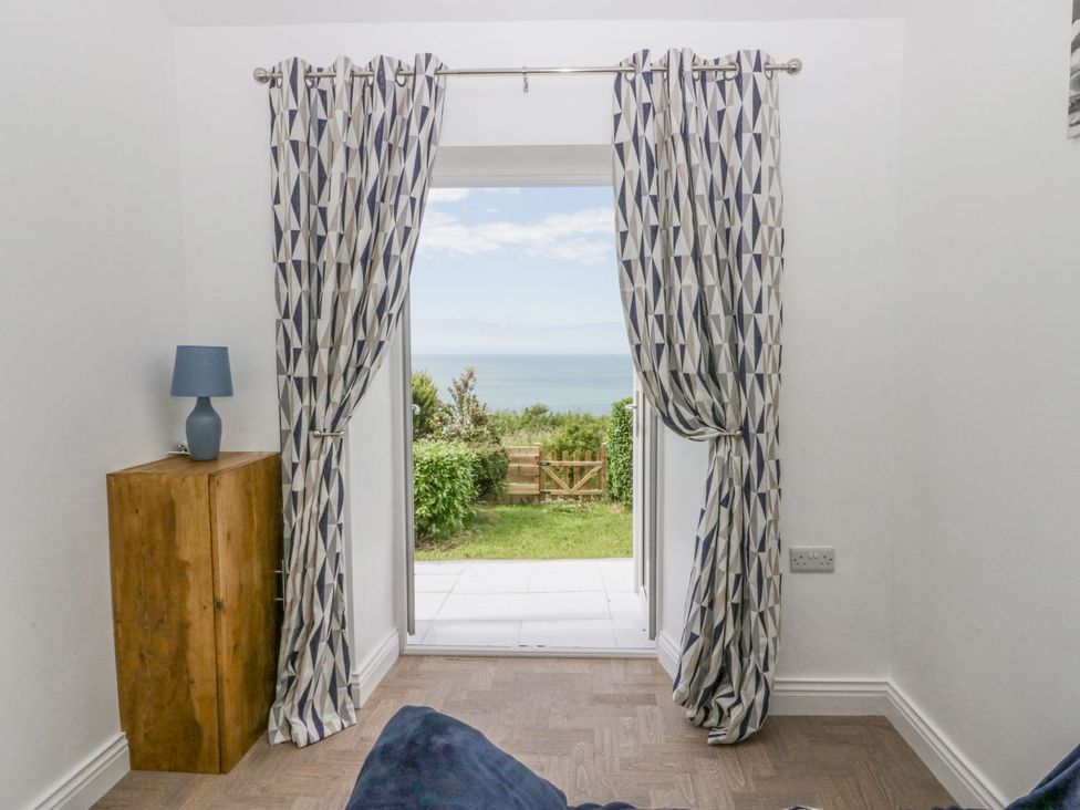 A room with a curtain and lamp overlooking a garden at Victroneen Cottage Whitehaven
