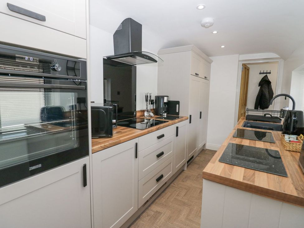 A kitchen with appliances and cabinets at Victroneen Cottage Whitehaven