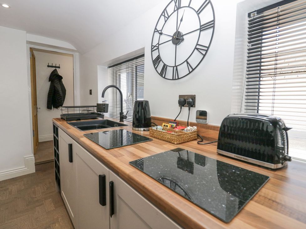 A kitchen with black appliances and wood countertop at Victroneen Cottage in Whitehaven