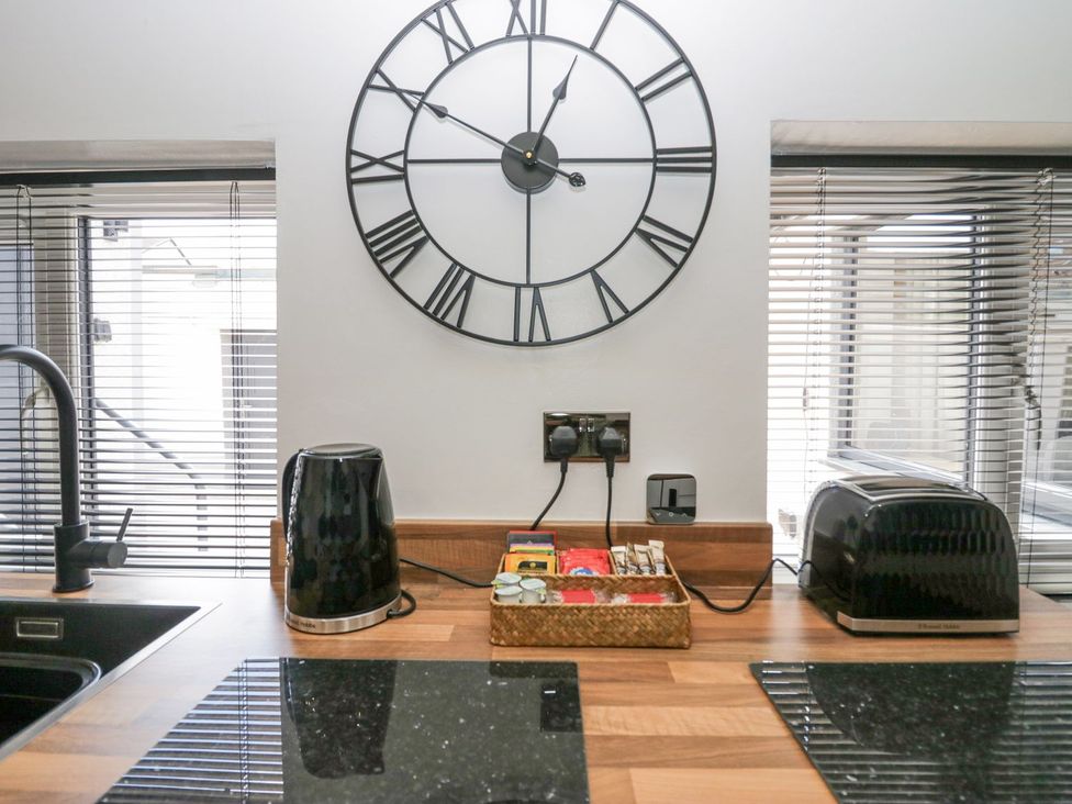 A kitchen with kettle, toaster, and clock at Victroneen Cottage in Whitehaven