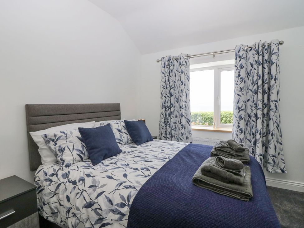 A bedroom with a bed and curtains at Victroneen Cottage in Whitehaven