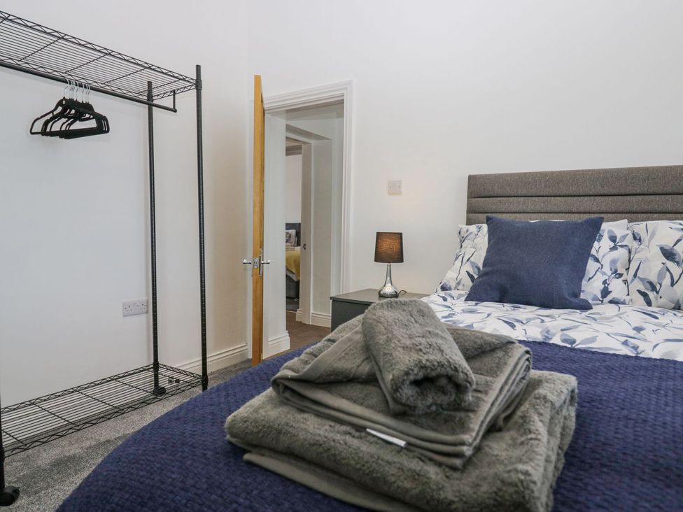 A bedroom with a bed and towels arranged at Victroneen Cottage, Whitehaven