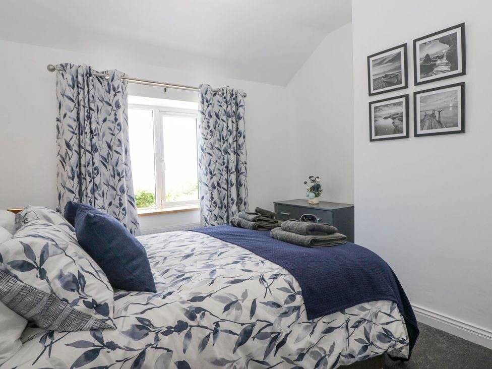 A bedroom with a bed and nightstand at Victroneen Cottage in Whitehaven