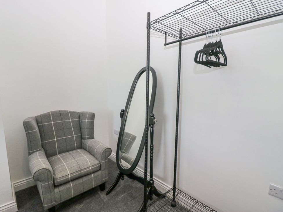 A dressing room with a chair and a mirror at Victroneen Cottage in Whitehaven