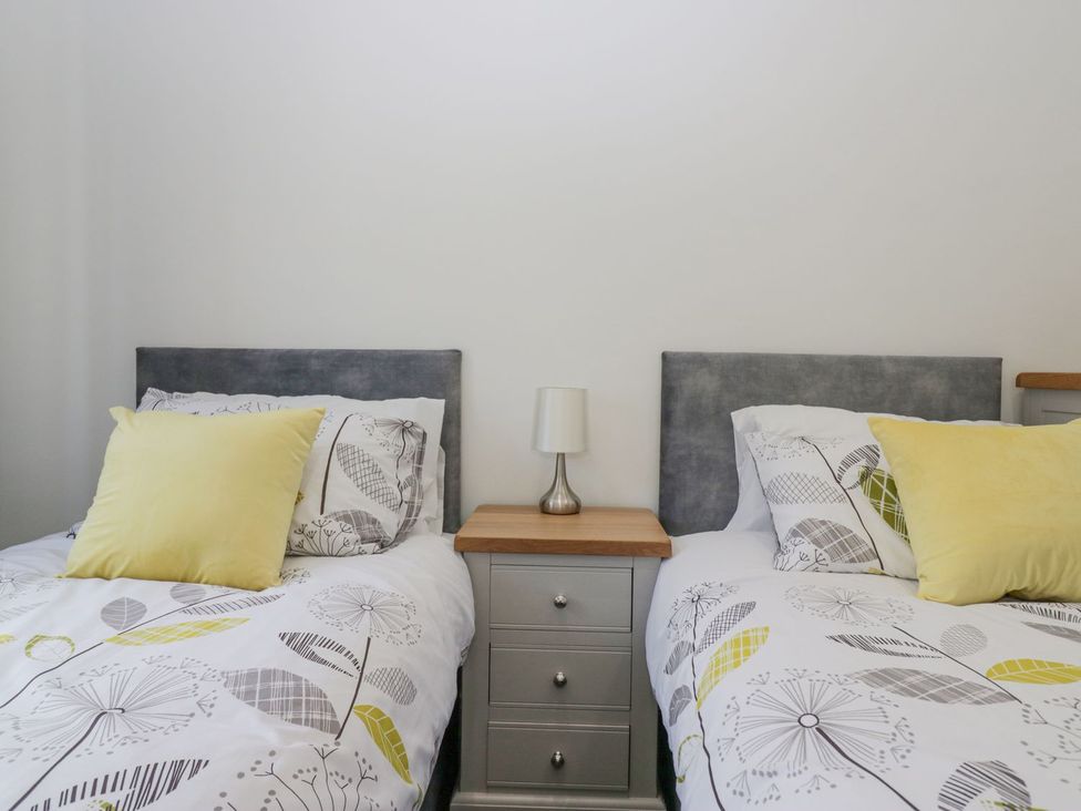 A bedroom with two beds and a bedside table at Victroneen Cottage Whitehaven