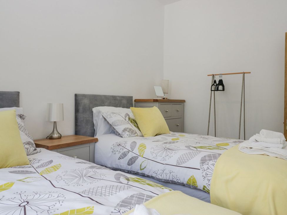 A bedroom with twin beds and a clothes rack at Victroneen Cottage in Whitehaven