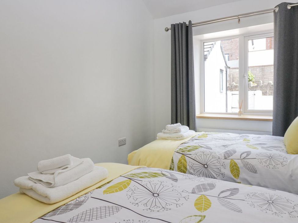 A bedroom with two beds and a window at Victroneen Cottage in Whitehaven