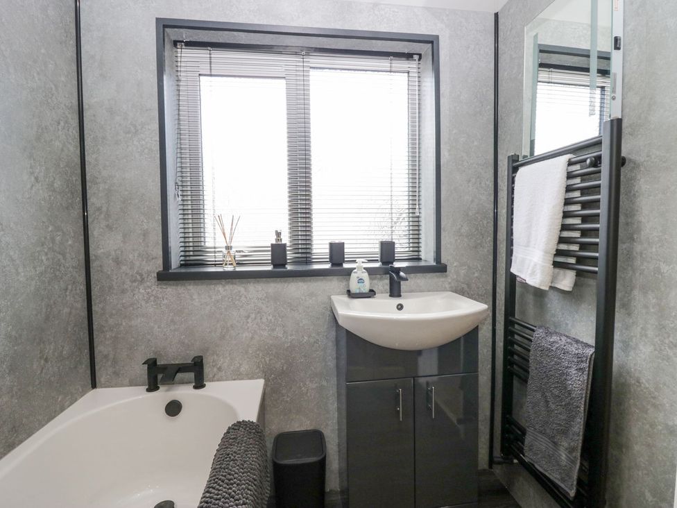 A bathroom with a bath tub and sink at Victroneen Cottage in Whitehaven