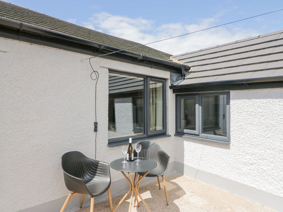 An outdoor seating area with a table and two chairs at Victroneen Cottage in Whitehaven