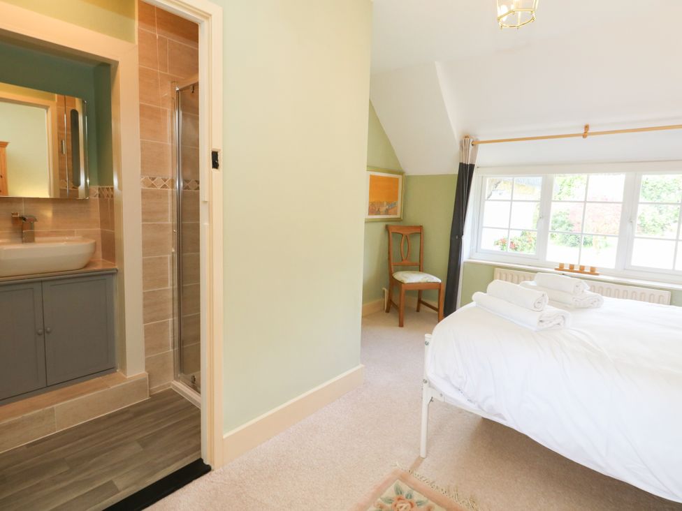 A bedroom with a bed and bathroom area at Rose Cottage in Osmington