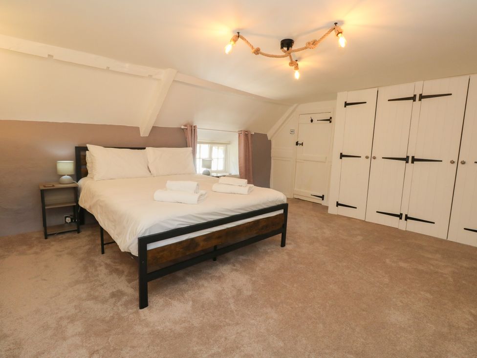 A bedroom with a bed and wardrobe at Rose Cottage in Osmington