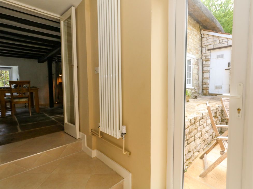 A dining area with a radiator and doors to an outdoor space at Rose Cottage in Osmington