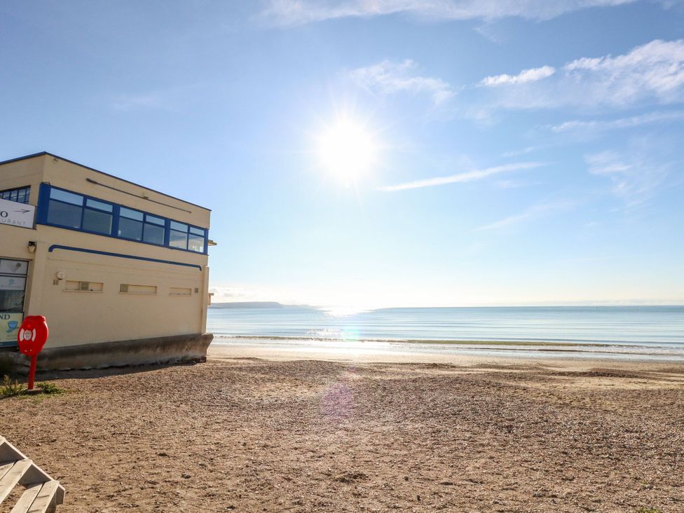 A beach with a building and water at Rose Cottage in Osmington