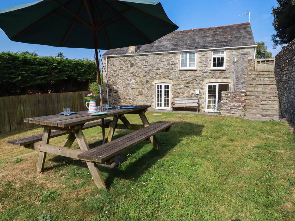 A garden with a picnic table and stone house at Bryher Cottage in St Mawgan