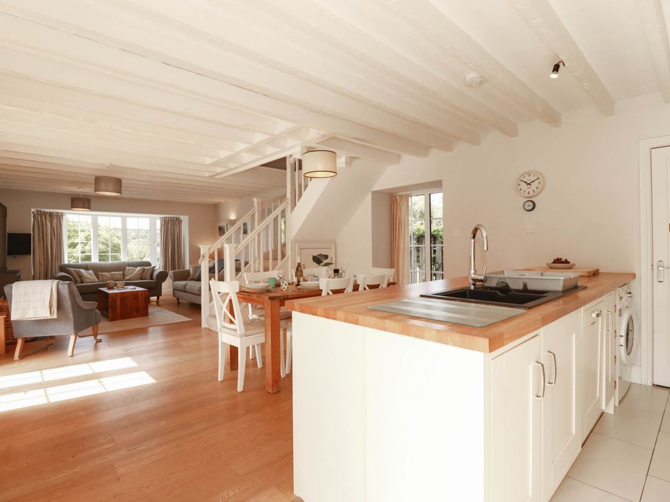 A living room with a sofa, dining table and kitchen area at Bryher Cottage St Mawgan