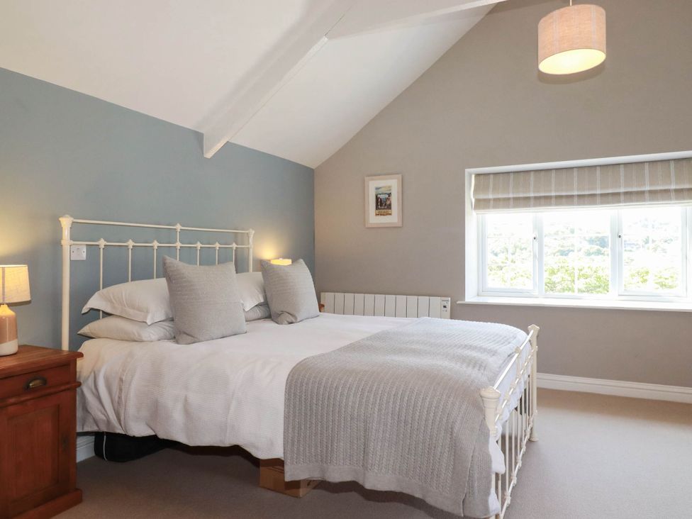 A bedroom with a bed and window at Bryher Cottage St Mawgan