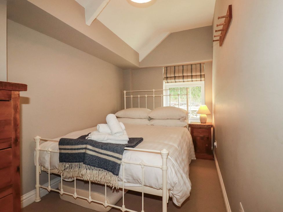 A bedroom with a bed and a lamp at Bryher Cottage St Mawgan