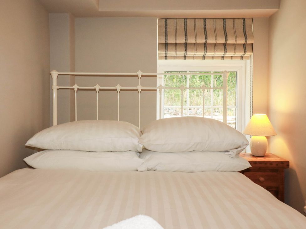 A bedroom with a bed and window at Bryher Cottage in St Mawgan