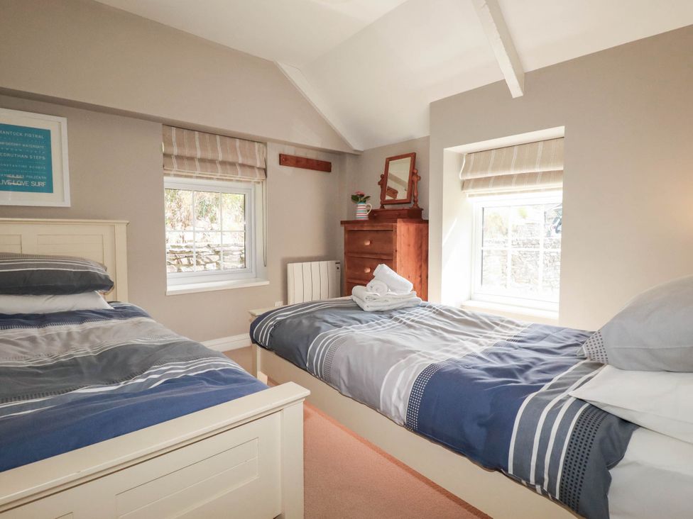 A bedroom with two beds and a dresser at Bryher Cottage St Mawgan