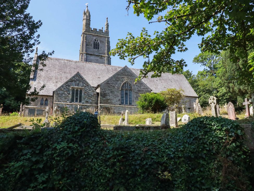 A church with gravestones and trees at Bryher Cottage St Mawgan