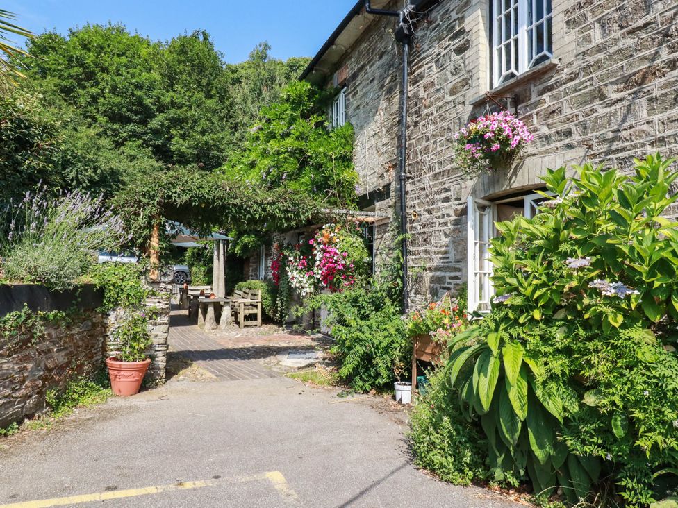 An outdoor area with a stone house and flowers at Bryher Cottage in St Mawgan