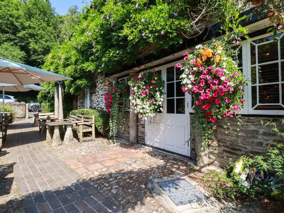 An outdoor seating area with flowers and tables at Bryher Cottage in St Mawgan