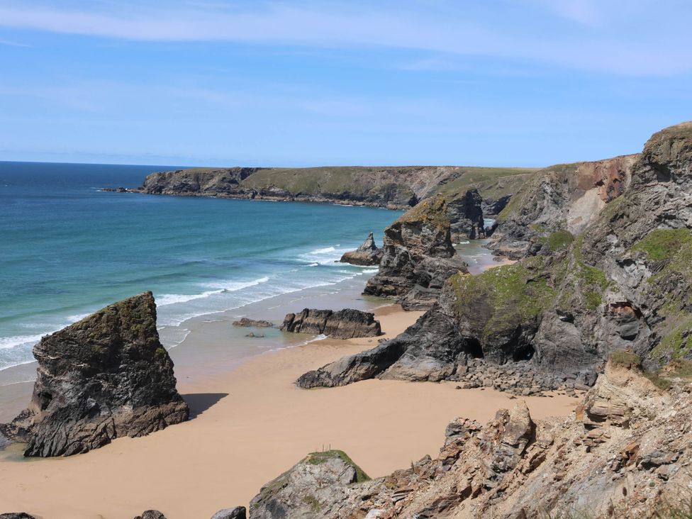 A view of a beach with cliffs and rocks at Bryher Cottage St Mawgan