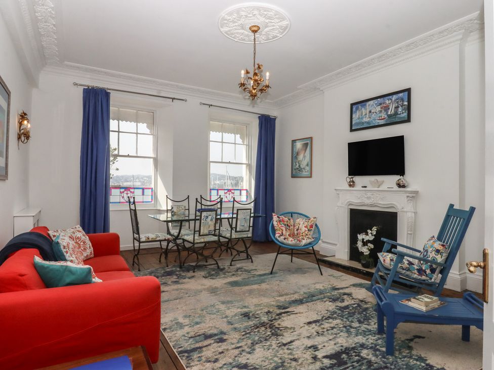 A living room with a red sofa and dining table at Marina Court Apartment in Torquay