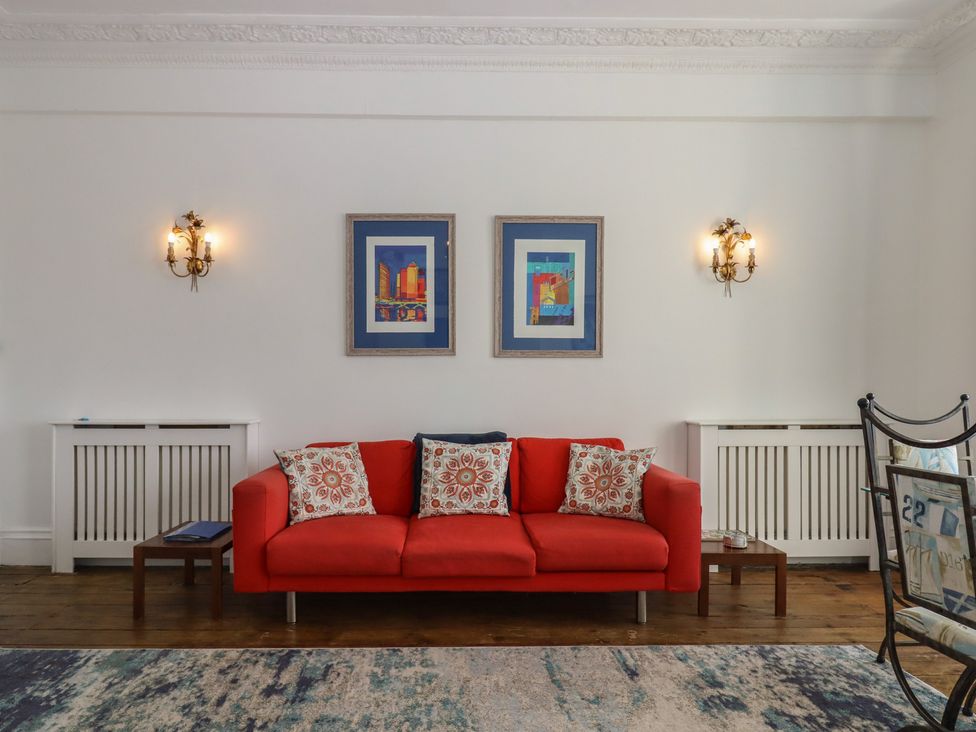 A living room with a red sofa and framed pictures at Marina Court Apartment in Torquay