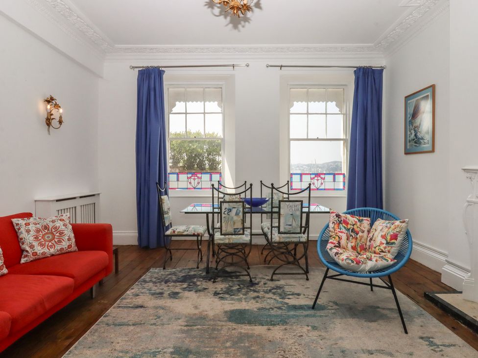 A living room with a red sofa and blue curtains at Marina Court Apartment in Torquay