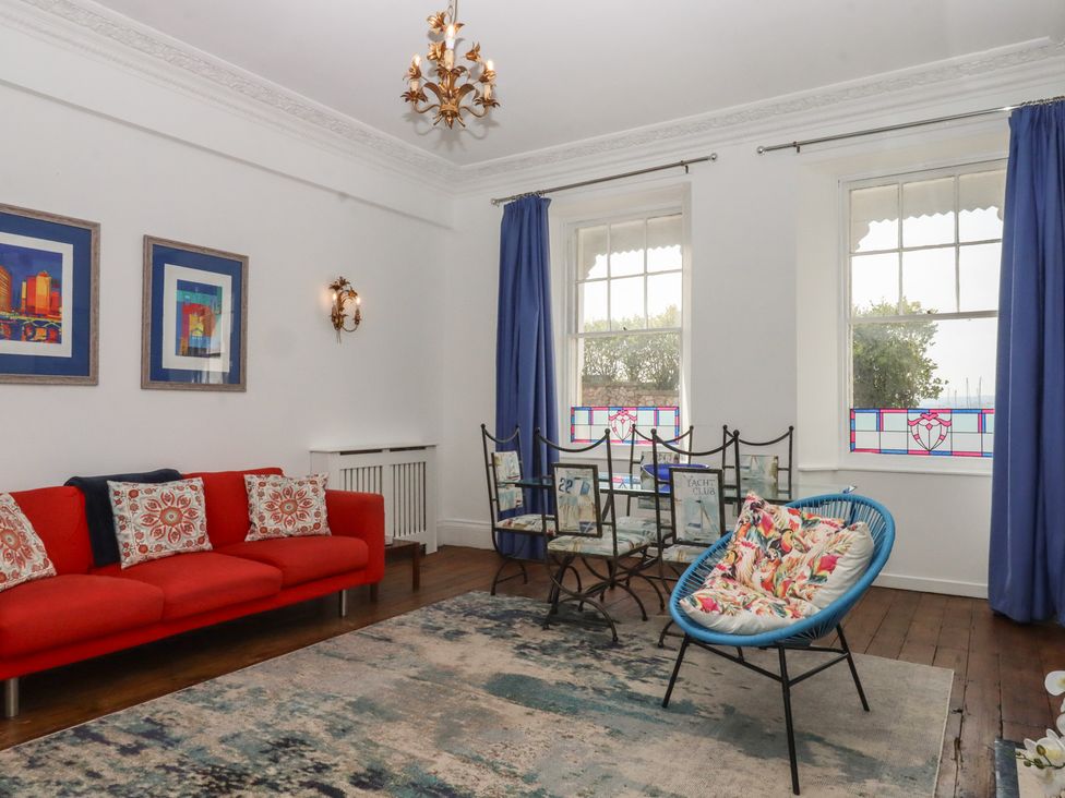 A living room with a red sofa and blue armchair at Marina Court Apartment in Torquay