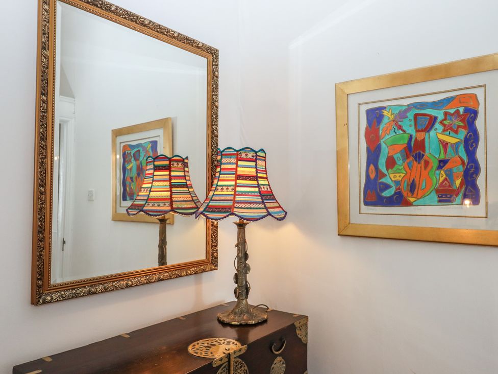 A room with a lamp, mirror, and artwork at Marina Court Apartment in Torquay