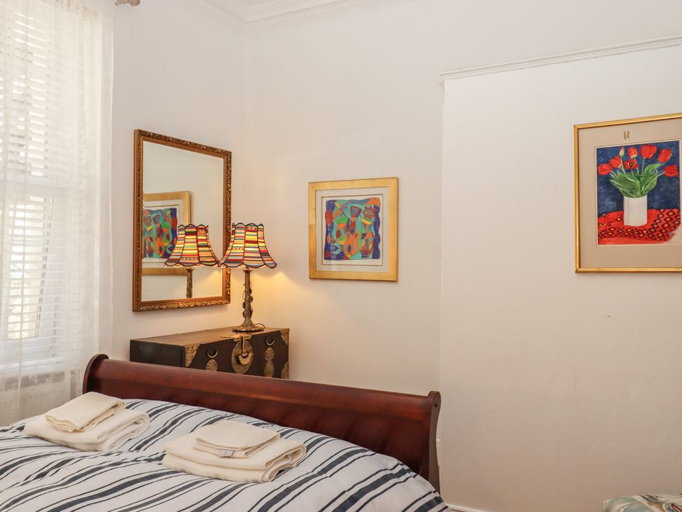 A bedroom with a bed, lamp, and artwork at Marina Court Apartment in Torquay