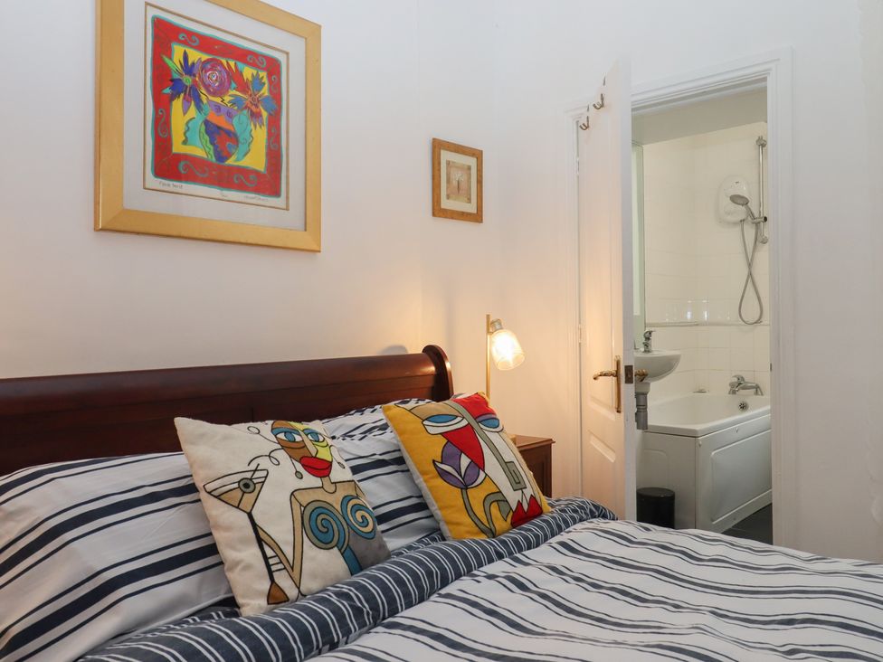 A bedroom with a bed and doorway to a bathroom at Marina Court Apartment in Torquay